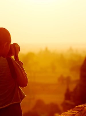 Image of woman taking photo of temple at sunrise